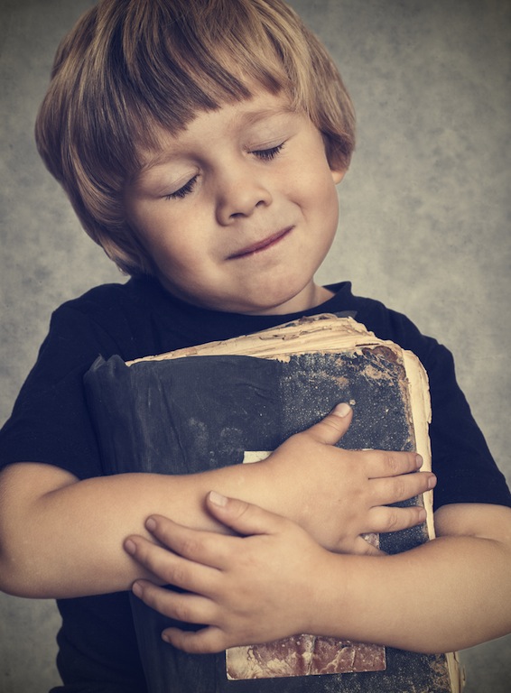 Little boy hugging an old book